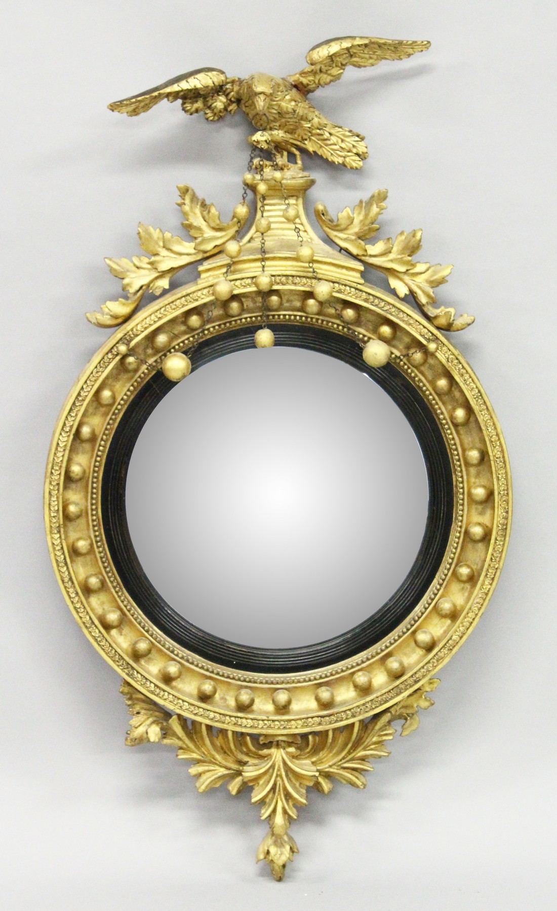 A REGENCY GILT WOOD CONVEX MIRROR with eagle cresting, ball applied frame and curved decoration to