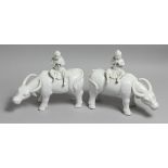 A PAIR OF CHINESE BLANC DE CHINE FIGURES OF BOYS SEATED ON WATER BUFFALO. 11ins long.