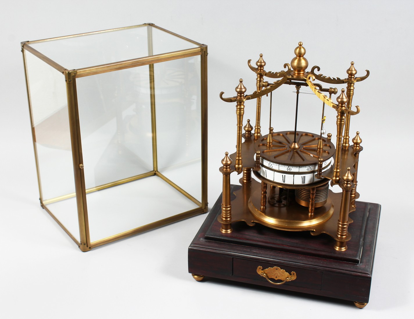 AN UNUSUAL TABLE CLOCK MODELLED AS A CAROUSEL housed under a glass case with a drawer to the