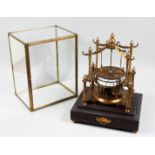 AN UNUSUAL TABLE CLOCK MODELLED AS A CAROUSEL housed under a glass case with a drawer to the