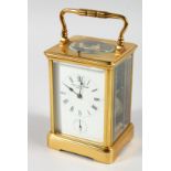 A FRENCH BRASS CARRIAGE CLOCK with eight day movement, striking on a gong enamel dial with