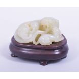 A CHINESE QING DYNASTY CELADON JADE CARVED THREE LIONS, on a fitted hardwood stand, jade 9cm x 8.