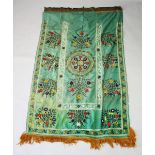 A SILK SUZANI TEXTILE, green ground embroidered with floral motifs and verses of the quran in