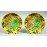 A PAIR OF CHINESE YELLOW GROUND SANCAI DISHES, the centre with dragon and phoenix, with six