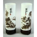 A PAIR OF CHINESE CYLINDRICAL PORCELAIN BRUSH POTS, on fitted hardwood stands, brush pot 13cm high.