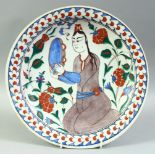 A TURKISH OTTOMAN IZNIK PLATE, decorated with a figure and flora, 31.5cm diameter.