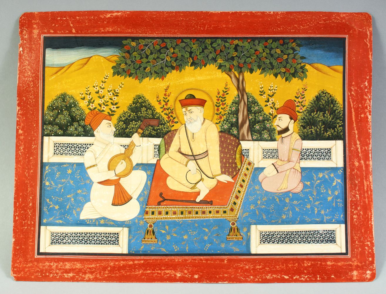 A LARGE INDIAN MINIATURE PAINTING ON PAPER, depicting a seated holy man with a musician and