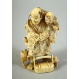 A JAPANESE CARVED IVORY NETSUKE, of a father and son, the father holding a turtle with dogs at his
