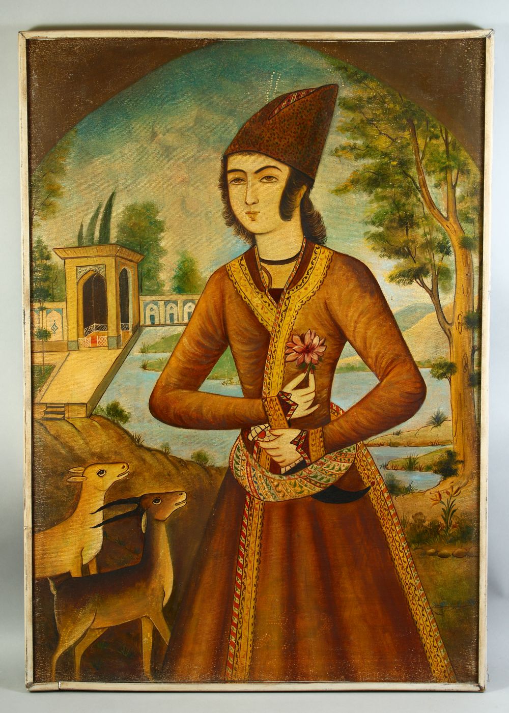 A 20TH CENTURY PERSIAN OIL PAINTED PORTRAIT ON CANVAS, of a royal figure in a garden with deer,