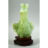 A CHINESE CARVED JADE VASE AND COVER on a fitted hardwood stand, the vase carved with foo dogs,