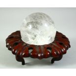 A ROCK CRYSTAL SPHERE WITH A HARDWOOD STAND, sphere approx 9cm diameter.