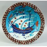 A TURKISH OTTOMAN IZNIK PLATE, decorated with a boat and fish, 31cm diameter.