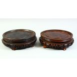 TWO MATCHED CHINESE CARVED AND PIERCED CIRCULAR HARDWOOD STANDS, both housing a base of approx.