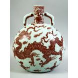 A CHINESE RED UNDERGLAZE PORCELAIN TWIN HANDLE MOONFLASK, decorated with a dragon amongst stylised