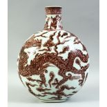 A CHINESE UNDER GLAZE RED PORCELAIN MOON FLASK, painted with a dragon amongst stylised flames and