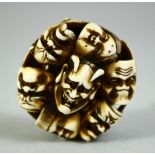 A JAPANESE CARVED IVORY NETSUKE, carved as a roundel of noh masks, signed, 4.5cm.