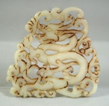 A CHINESE CARVED AND PIERCED AMULET DEPICTING A DRAGON, 8cm x 8cm.