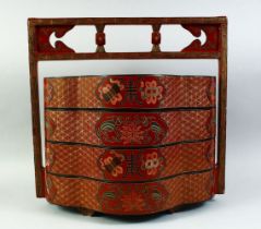 A CHINESE RED LACQUER FOUR TIER STACKING BOX with handle, the cases decorated with auspicious