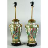 A PAIR OF CHINESE CANTON FAMILLE ROSE PORCELAIN LAMP VASES, painted with panels of figures as well