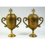 A PAIR OF INDIAN ENGRAVED AND CHASED BRASS LIDDED PEDESTAL CUPS, with twin handles, the lids with