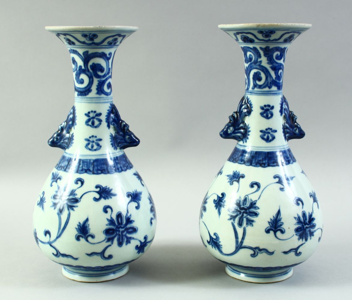 A PAIR OF CHINESE BLUE AND WHITE PORCELAIN VASES, with formed handles and floral decoration, 27.