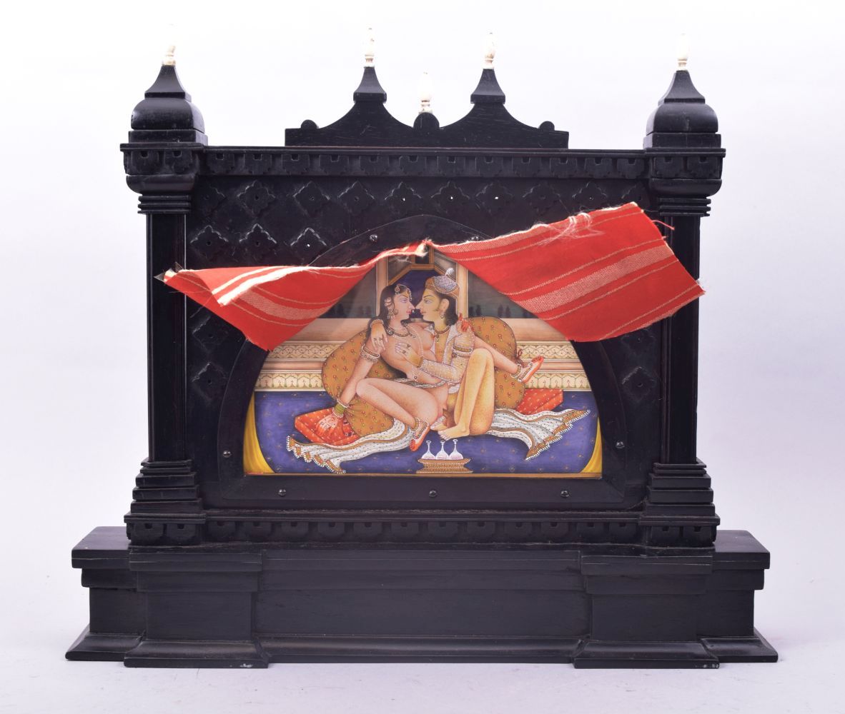 A SMALL INDIAN EBONISED TABLE SCREEN, inset with a painting of an erotic scene with pierced silver