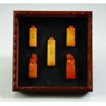 A SET OF FIVE SMALL CHINESE STONE SEALS, contained in a fitted wood box with a sliding cover, the