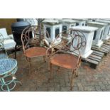 A pair of wrought iron garden armchairs.