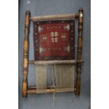 A partly woven Persian rug on a small loom.