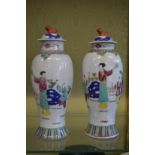 A pair of Famille Rose baluster shaped vases and covers.