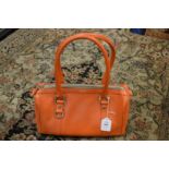 A Gucci orange leather handbag.