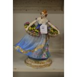 A porcelain figure of a lady holding two baskets of flowers.