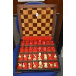 A chess board / box containing various chess pieces.
