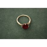 A gold ring set with a red coloured stone.