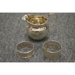 A silver jug and napkin rings.