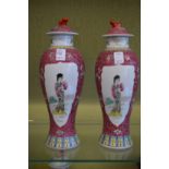 A pair of Chinese Famille Rose baluster shaped vases and covers decorated with female figures.