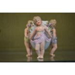 A small Dresden vase modelled as three cherubs holding an urn.