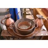 A pair of old copper harvest jugs and three preserve pans.