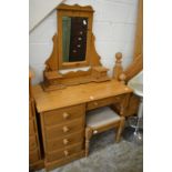 A pine dressing table with mirror and stool.