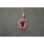 A gold chain with an amethyst pendant.
