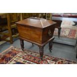 A good Regency mahogany sarcophagus shaped cellarette on turned and reeded legs with brass castors.