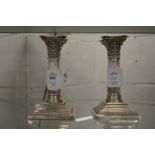 A pair of plated Corinthian column style candlesticks.