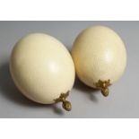 A PAIR OF OSTRICH EGGS each with an ormolu pineapple form finial.`