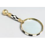 A MAGNIFYING GLASS with chequered handle.