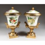 A PAIR OF PORCELAIN URN SHAPED VASES AND COVERS painted with fruit. 14ins high.