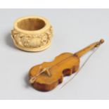 A EUROPEAN CARVED IVORY SERVIETTE RING, 2ins diameter and a miniature violin (2).