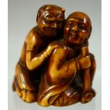 A JAPANESE CARVED AND STAINED IVORY NETSUKE of a crouching man and an oni, 4cm high.