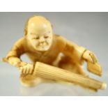 A JAPANESE CARVED IVORY NETSUKE of a seated man with a parasol in right hand and brush in his