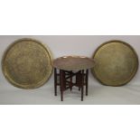 THREE LARGE ISLAMIC METAL TRAYS AND A CARVED WOOD STAND, largest tray 75cm diameter.