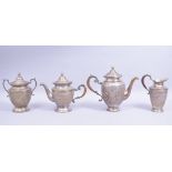 A GOOD PERSIAN WHITE METAL FOUR PIECE TEA SET, the body of each with panels of flora, each with part